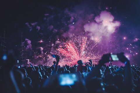 Eine feiernde Menschenmenge bei Nacht mit Feuerwerk.